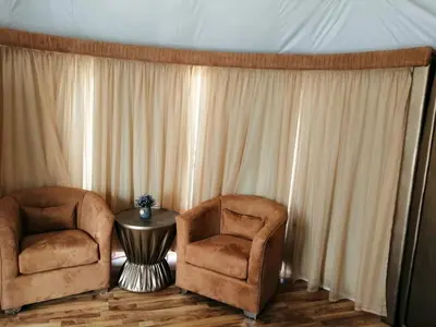 two chairs and a table in a room with curtains at Mazayen Rum Camp in Wadi Rum