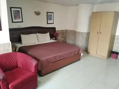 a bedroom with a bed and a red chair at Amman Palace Hotel in Amman