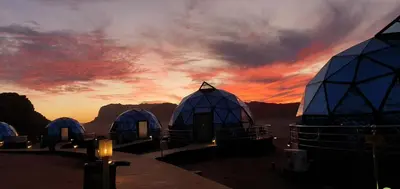 a group of domes with a sunset in the background at Memories Aicha Luxury Camp in Wadi Rum