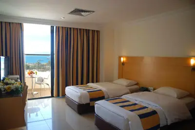 a hotel room with two beds and a balcony at Mina Hotel in Aqaba
