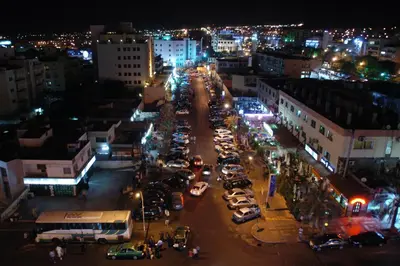 a busy city street at night with cars parked at Mina Hotel in Aqaba