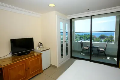 a bedroom with a flat screen tv and a balcony at Mina Hotel in Aqaba
