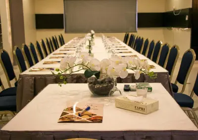 a row of long tables with vases of flowers on them at Capri Hotel Suites in Amman