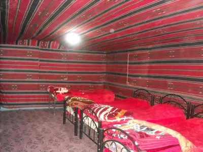 a room with two beds with red sheets at Bedouin House Camp in Wadi Rum