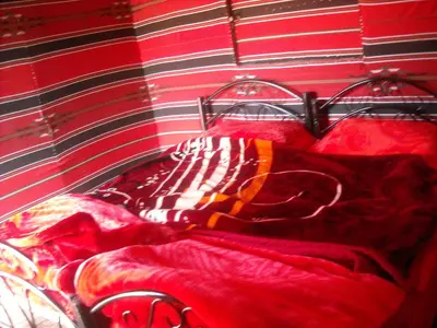 a bed in a room with a red blanket at Bedouin House Camp in Wadi Rum