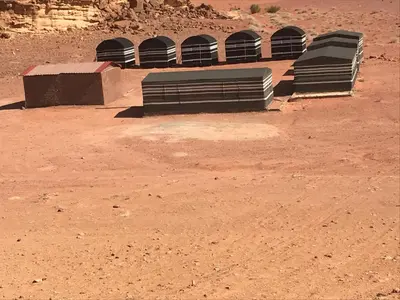 a row of benches sitting in the desert at Bedouin House Camp in Wadi Rum