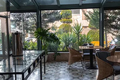 a patio with tables and chairs and a large window at Guest House Hotel Amman by FHM in Amman
