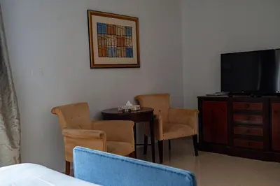a room with a tv and chairs and a table at Guest House Hotel Amman by FHM in Amman