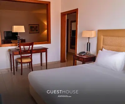 a hotel room with a bed and a desk and a mirror at Guest House Hotel Amman by FHM in Amman
