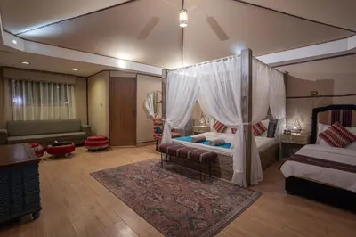 a bedroom with a canopy bed and a living room at Rahayeb Desert Camp in Wadi Rum