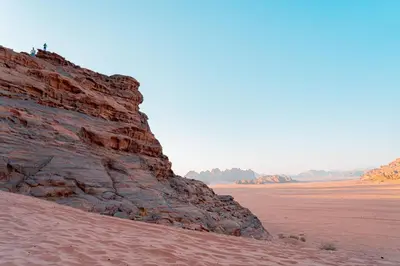 a cliff in the desert next to a dirt field at Rahayeb Desert Camp in Wadi Rum