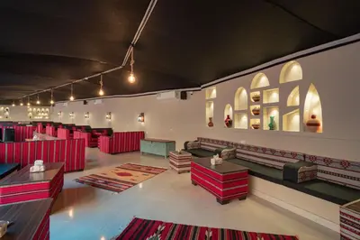 a room with red chairs and tables and red rugs at Rahayeb Desert Camp in Wadi Rum