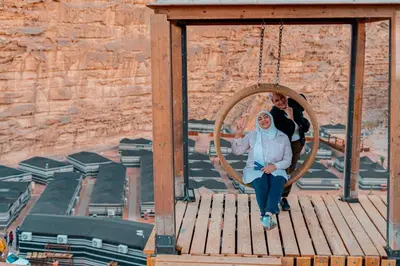 a man and a woman sitting in a swing at Rahayeb Desert Camp in Wadi Rum
