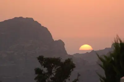 a sunset in the mountains with the sun setting at B&B Petra Fig Tree Villa in Wadi Musa
