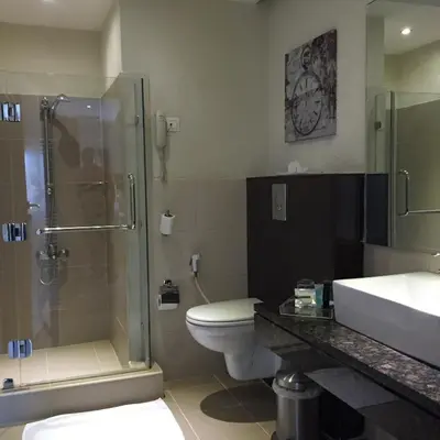 a bathroom with a shower and a toilet and a sink at Crystal Hotel in Amman