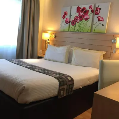a bed in a hotel room with a flower painting on the wall at Crystal Hotel in Amman