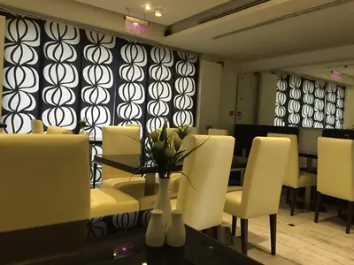 a dining room with white chairs and a table with flowers at Crystal Hotel in Amman