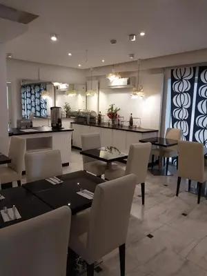 a dining room with tables and chairs and a kitchen at Crystal Hotel in Amman