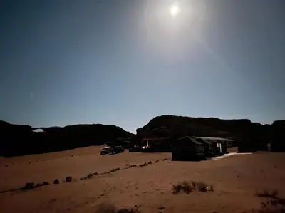 a view of a desert with the moon in the sky at Black Irish Camp And Tours in Wadi Rum
