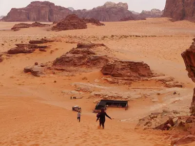 a man and a child walking through the desert at Black Irish Camp And Tours in Wadi Rum