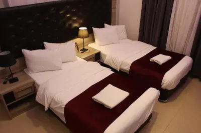 two beds in a hotel room with towels on them at Virginia Hotel in Amman