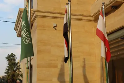 two flags are flying in front of a building at Virginia Hotel in Amman