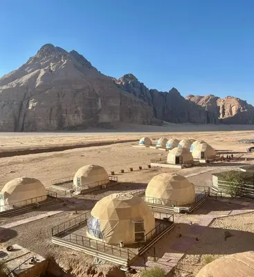 a group of tents in a desert with a mountain at Jamal Rum desert in Wadi Rum