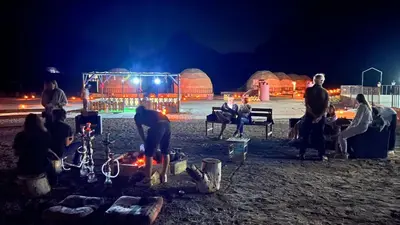 a group of people sitting around a campfire at night at Jamal Rum desert in Wadi Rum