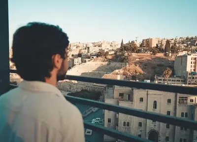 a man standing on a balcony looking at the city at Amman Pasha Hotel in Amman