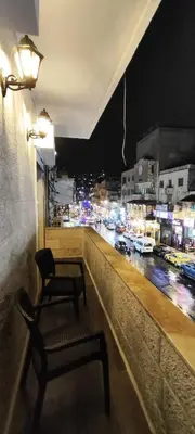 a chair on a balcony with a view of a city at The Boutique Hotel Amman in Amman