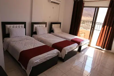two beds in a room with a large window at Weekend Hotel in Aqaba