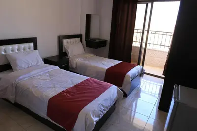 a hotel room with two beds and a balcony at Weekend Hotel in Aqaba