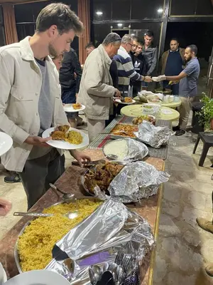 a group of people standing around a buffet of food at Ein lahda camp-site in Dana