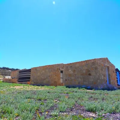 a brick building sitting on top of a grass field at Ein lahda camp-site in Dana