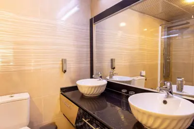 a bathroom with two sinks and a toilet and a mirror at Petra Palace Hotel in Wadi Musa