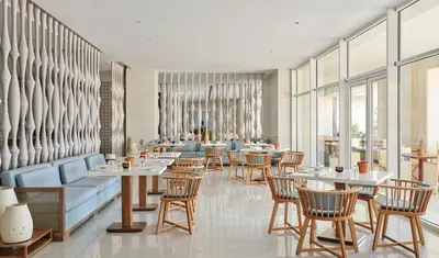 a restaurant with tables and chairs and windows at Hyatt Regency Aqaba Ayla Resort in Aqaba