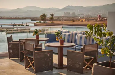 two tables and chairs on a balcony with a view of the water at Hyatt Regency Aqaba Ayla Resort in Aqaba