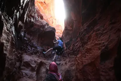 two people climbing in a cave in a canyon at Bedouin Expedition in Wadi Rum