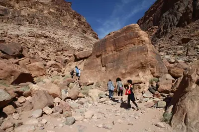 a group of people walking on rocks in a canyon at Bedouin Expedition in Wadi Rum
