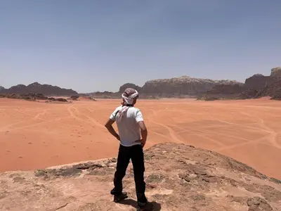 a man standing on a rock in the desert at Bedouin Holidays Camp and Jeep Tours in Wadi Rum