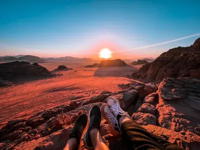 a person laying on a rock in the desert at sunset at Bedouin Holidays Camp and Jeep Tours in Wadi Rum
