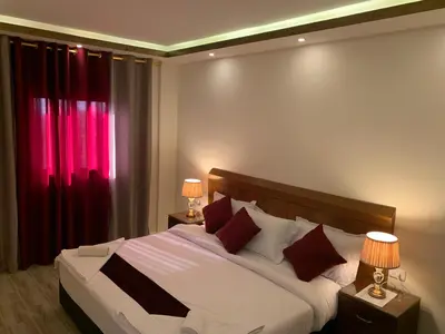 a bedroom with a large bed with red curtains at Petra Sky Hotel in Wadi Musa