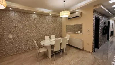 a dining room with a table and chairs and a wall at Western Gate Residence 2 Amman in Amman