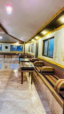 a room with couches and a table and windows at Miral Night Camp in Wadi Rum