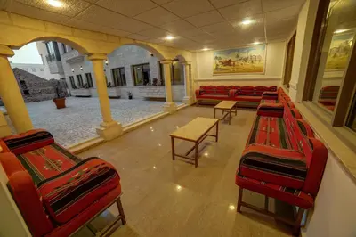an empty waiting room with red chairs and tables at Crystal Hotel By FHM in Aqaba