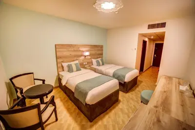 a hotel room with two beds and a table and chairs at Crystal Hotel By FHM in Aqaba