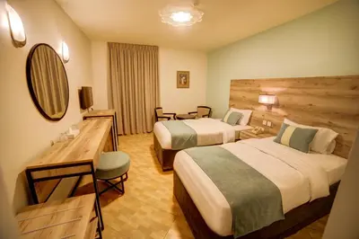 a hotel room with two beds and a mirror at Crystal Hotel By FHM in Aqaba