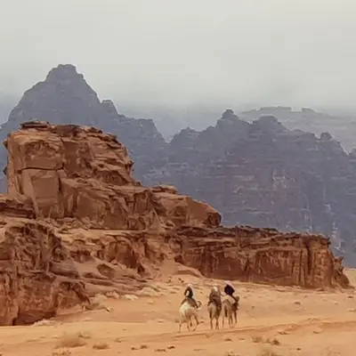 three people riding on camels in the desert at Real Bedouin Experience Tours & Camp in Wadi Rum