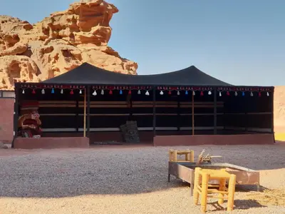 a building in the desert with two chairs in front at Real Bedouin Experience Tours & Camp in Wadi Rum