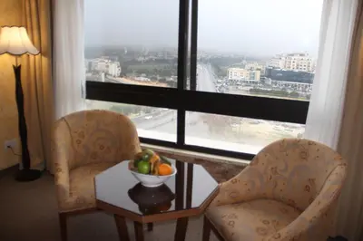 two chairs and a bowl of fruit on a table in front of a window at Saray Hotel Amman in Amman